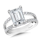 A stunning emerald-cut center is supported by diamond-accented prongs, resting above a wide split shank.