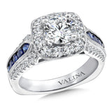 Diamond halo engagement ring mounting with milgrain detailing and blue sapphire side stones set in 14k white gold.