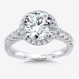 A round center is surrounded by a diamond halo and diamond side stones set in 14k white gold.