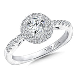 A double halo accentuates the center stone, while a delicate band of pave-set diamonds cascades down the finger.