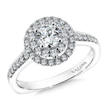 A double halo accentuates the center stone, while a delicate band of pave-set diamonds cascades down the finger.