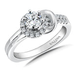 In this romantic design, bands of diamonds and polished gold form a love knot  that embraces the center stone.