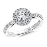 A double halo accentuates the center stone, while a delicate band of pave-set diamonds cascades down the finger.